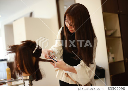 Image of a hairdresser practicing cutting hair Image of a hairdresser practicing cutting hair 83509098
