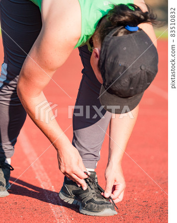 Asian runner in green singlet stopped for lacing shoe Asian runner in green singlet stopped for lacing shoe 83510832