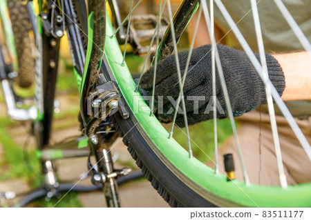Bike mechanic man repairs bicycle in bicycle repair shop, outdoor. Hand of cyclist bicyclist examines, fixes modern cycle transmission system. Bike maintenance, sport shop concept. Bike mechanic man repairs bicycle in bicycle repair shop, outdoor. Hand of cyclist bicyclist examines, fixes modern cycle transmission system. Bike maintenance, sport shop concept. 83511177