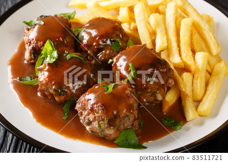 Boulets a la Liegeoise a Classic Belgium Meatball in apple sauce and French fries closeup in the plate. Horizontal Boulets a la Liegeoise a Classic Belgium Meatball in apple sauce and French fries closeup in the plate. Horizontal 83511721