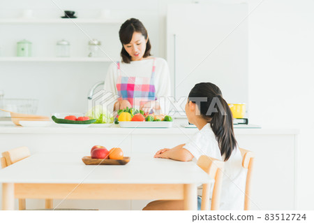 年輕的母親在廚房做飯，小學女孩在餐廳 83512724