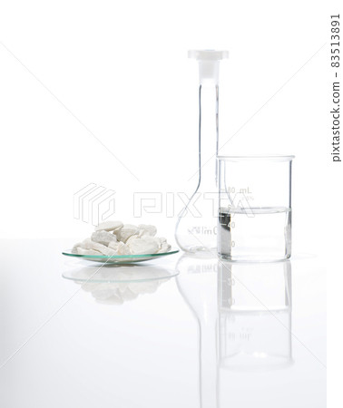Close up chemical ingredient on white laboratory table. Calcium carbonate Chip in Chemical Watch Glass place next to beaker with alcohol and Volumetric flask. Side View 83513891