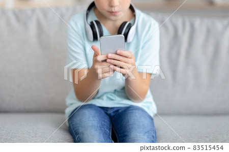 Unrecognizable kid using mobile phone at home Unrecognizable kid using mobile phone at home 83515454