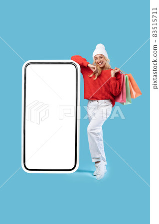 Woman leaning on white empty smartphone screen holding bags Woman leaning on white empty smartphone screen holding bags 83515711
