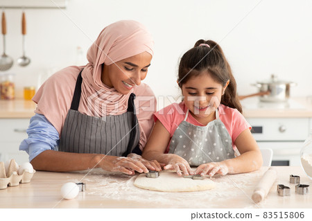 Cheerful Muslim Mother In Hijab Baking With Her Little Daughter In Kitchen Cheerful Muslim Mother In Hijab Baking With Her Little Daughter In Kitchen 83515806
