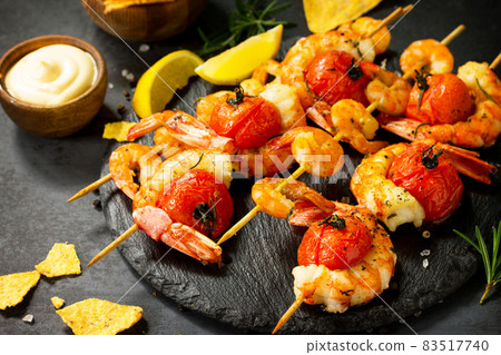 Delicious Grilled shrimps with spice, lemon and sauce served on a slate board served with nachos chips. Seafood. 83517740