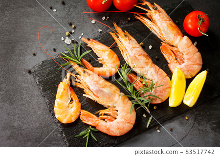 Seafood. Raw shrimps with spice, tomatoes and lemon on a slate board. Seafood. Raw shrimps with spice, tomatoes and lemon on a slate board. 83517742