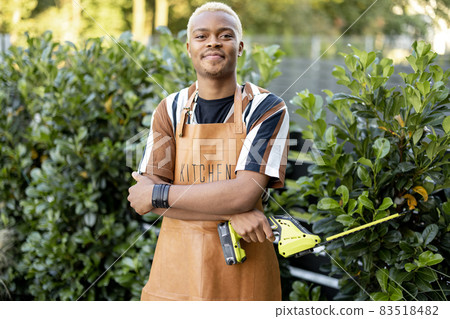 Man cuts plant with gardening scissors in garden Man cuts plant with gardening scissors in garden 83518482