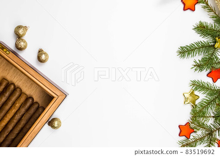 Open cigar humidor on white with holiday decoration. Christmas online shopping. Space for text. Smoking set accessories. luxury lifestyle flat lay 83519692