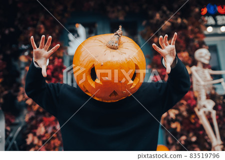 Girl with a pumpkin head scares at the camera Girl with a pumpkin head scares at the camera 83519796