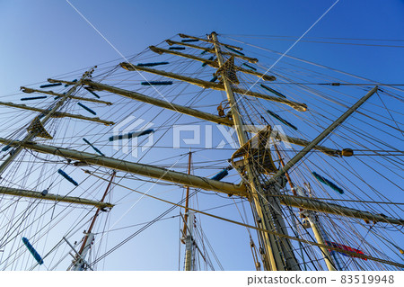 masts of a large sailing ship with ropes on a background of blue sky masts of a large sailing ship with ropes on a background of blue sky 83519948
