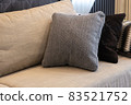 Cozy interior details. Decorative pillows in neutral colors, plaid on beige textile sofa. Home comfort concept, textiles, decorative accessories for apartment interior decoration 83521752