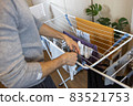 A man hangs up the washed clothes on the dryer, which is in a room in the apartment. Hygiene concept, helping men to women around the house, changing roles, daily cleaning. Horizontal 83521753