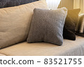 Cozy interior details. Decorative pillows in neutral colors, plaid on beige textile sofa, warm highlight. Home comfort concept, textiles, decorative accessories for apartment interior decoration 83521755