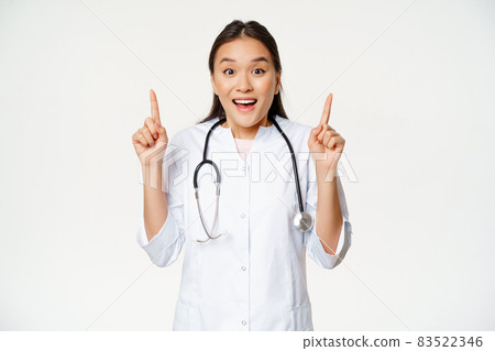 Excited smiling nurse, female doctor in medical uniform pointing up, showing promo sale, healthcare clinic discount, standing over white background Excited smiling nurse, female doctor in medical uniform pointing up, showing promo sale, healthcare clinic discount, standing over white background 83522346