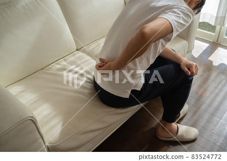 A man sitting on the sofa and putting his hand on his waist A man sitting on the sofa and putting his hand on his waist 83524772
