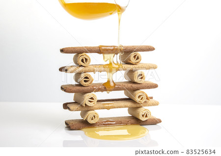 Fresh flower honey flows and drips onto herdry crispy cookie sticks. Dessert snack food. Fresh flower honey flows and drips onto herdry crispy cookie sticks. Dessert snack food. 83525634