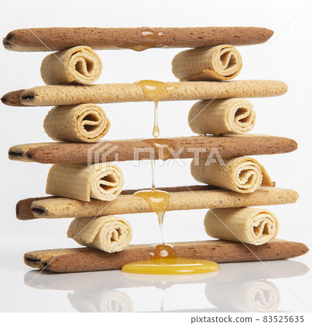 Fresh flower honey flows and drips onto herdry crispy cookie sticks. Dessert snack food. Fresh flower honey flows and drips onto herdry crispy cookie sticks. Dessert snack food. 83525635