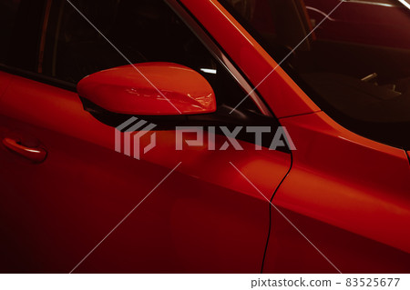 Close-up side mirrors of red car for parking safety. 83525677