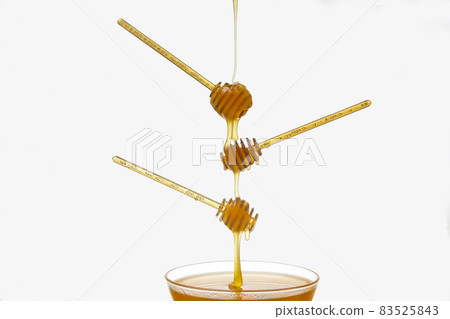 Fresh flower honey drips from a spoon into a spoon on a white background. Organic vitamin food. Fresh flower honey drips from a spoon into a spoon on a white background. Organic vitamin food. 83525843