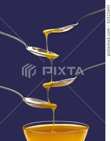 Fresh floral honey drips from a spoon into a spoon on a blue background. Organic vitamin food. Fresh floral honey drips from a spoon into a spoon on a blue background. Organic vitamin food. 83525845