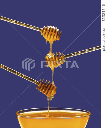 Fresh floral honey drips from a spoon into a spoon on a blue background. Organic vitamin food. Fresh floral honey drips from a spoon into a spoon on a blue background. Organic vitamin food. 83525846