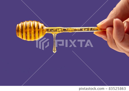 fresh fragrant honey drips from a spoon in hand on a blue background. organic vitamin nutrition fresh fragrant honey drips from a spoon in hand on a blue background. organic vitamin nutrition 83525863