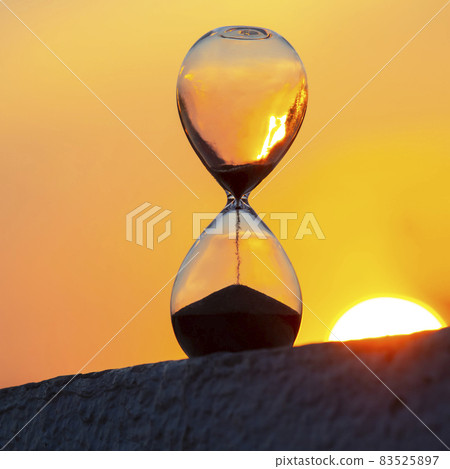 Hourglass counts the length of time against the background of the evening sun Hourglass counts the length of time against the background of the evening sun 83525897