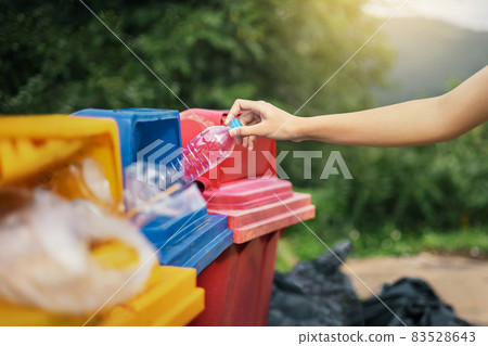 hand holding bottle plastic garbage into trash in park 83528643