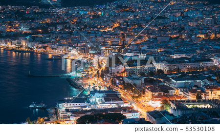 Kusadasi, Aydin Province, Turkey. Waterfront And Kusadasi Cityscape In Summer Evening. Night Scenic View Of Kusadasi Skyline At Aegean Coast, Turkey. 4K Kusadasi, Aydin Province, Turkey. Waterfront And Kusadasi Cityscape In Summer Evening. Night Scenic View Of Kusadasi Skyline At Aegean Coast, Turkey. 4K 83530108