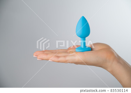 Woman holding a blue anal plug on a white background. Adult toy for alternative sex Woman holding a blue anal plug on a white background. Adult toy for alternative sex 83530114