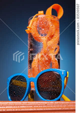 there is a glass with water on the stand, swimming glasses inside the glass, sunglasses are next to each other, the concept of vacation there is a glass with water on the stand, swimming glasses inside the glass, sunglasses are next to each other, the concept of vacation 83530507