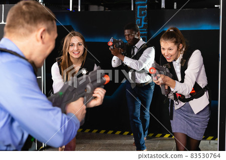 Group of colleagues holding laser pistols playing laser tag game 83530764