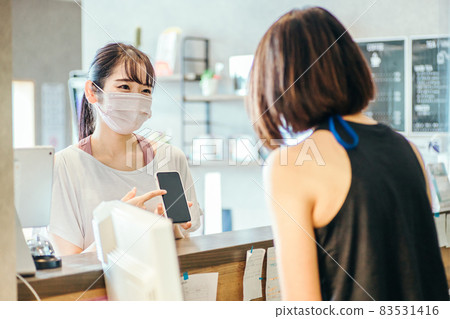 A woman (mask) who puts out a smartphone at the reception A woman (mask) who puts out a smartphone at the reception 83531416