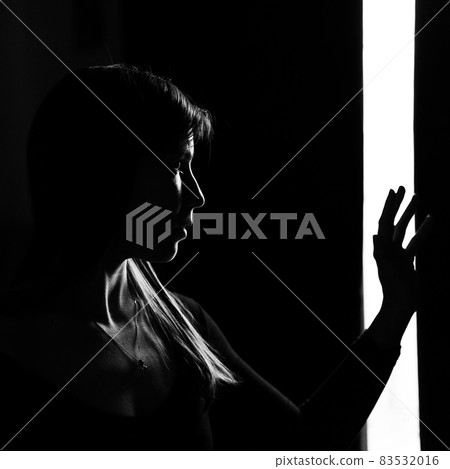 Portrait of a young woman in profile with dramatic light. Black and white photo. Portrait of a young woman in profile with dramatic light. Black and white photo. 83532016