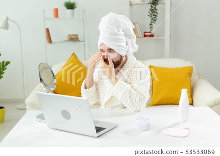 Young man with patches under the eyes at home. Concept of cosmetology for men. Spa at home, body and skin care Young man with patches under the eyes at home. Concept of cosmetology for men. Spa at home, body and skin care 83533069