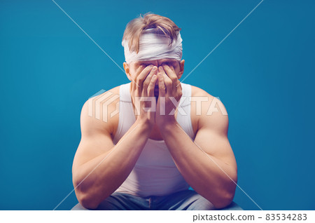 Young man with head injury in the doctor's office. Head bandaged with a bandage Young man with head injury in the doctor's office. Head bandaged with a bandage 83534283