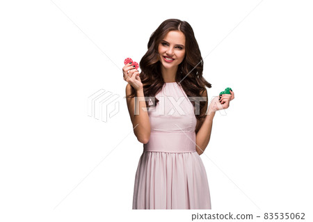Sexy woman in a chic gently pink dress holding colored poker chips. Woman winning Sexy woman in a chic gently pink dress holding colored poker chips. Woman winning 83535062