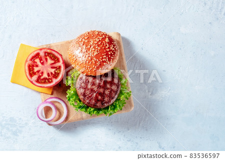 Beef burger ingredients on a wooden board with a place for text, shot from above 83536597