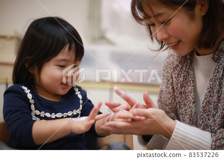 Mother applying moisturizing cream to a girl Mother applying moisturizing cream to a girl 83537226