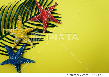 Summer Background concept with green leave and starfish decoration on yellow background Summer Background concept with green leave and starfish decoration on yellow background 83537398