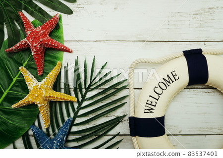 Summer concept with green leave, starfish and lifebuoy decoration on wooden background Summer concept with green leave, starfish and lifebuoy decoration on wooden background 83537401