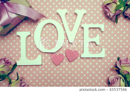 Love word alphabet and Gift box with roses bouquet with space copy on pink polka dot background Love word alphabet and Gift box with roses bouquet with space copy on pink polka dot background 83537566