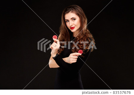Sexy curly hair brunette posing with chips in her hands, poker concept black background 83537676