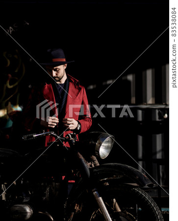 man in a coat near a vintage motorcycle man in a coat near a vintage motorcycle 83538084