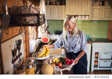 Happy senior woman unpacking shopping indoors at home, sustainable lifestyle. Happy senior woman unpacking shopping indoors at home, sustainable lifestyle. 83538283