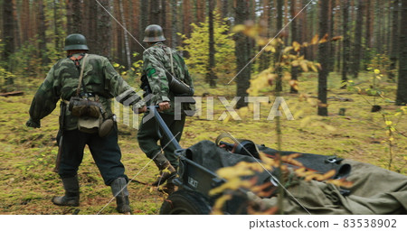 Historical Re-enactment. Re-enactors Dressed Like German Wehrmacht Infantry Soldiers Of World War II Pulling The Cart In Forest. Military Ammunition. Infantry Cart Handcart Infanteriekarren 83538902