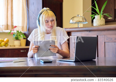 Female student in headphones using a laptop, studying at home Female student in headphones using a laptop, studying at home 83540026