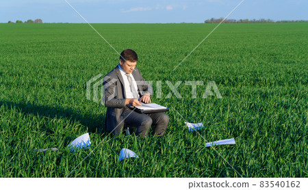 businessman works in a green field, freelance and business concept, green grass and blue sky as background 83540162