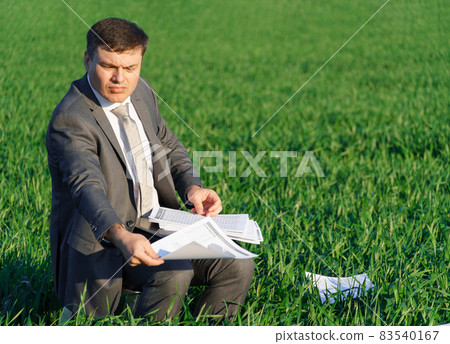 businessman works in a green field, freelance and business concept, green grass and blue sky as background businessman works in a green field, freelance and business concept, green grass and blue sky as background 83540167